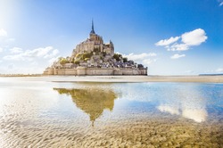 Panoramic view of famous Le Mont Saint-Michel tidal island on a sunny day with blue sky and clouds, Normandy, northern France