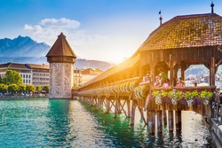 Historic city center of Lucerne with famous Chapel Bridge and Mount Pilatus summit in the background in golden evening light at sunset with blue sky and clouds, Canton of Lucerne, Switzerland