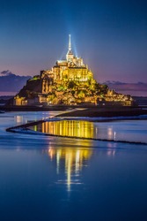 Scenic vertical view of famous Le Mont Saint-Michel tidal island in beautiful twilight during blue hour at dusk, Normandy, northern France