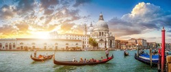 Beautiful view of traditional Gondolas on famous Canal Grande with historic Basilica di Santa Maria della Salute in the background in romantic golden evening light at sunset in Venice, Italy