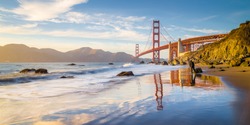 Classic panoramic view of famous Golden Gate Bridge seen from scenic Baker Beach in beautiful golden evening light on a sunny day with blue sky and clouds in summer, San Francisco, California, USA