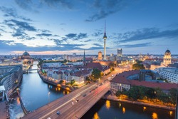 Classic aerial view of Berlin skyline with famous TV tower and Spree river in beautiful post sunset twilight during blue hour at dusk with dramatic clouds in summer, central Berlin Mitte, Germany