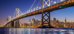 Classic panoramic view of famous Oakland Bay Bridge with the skyline of San Francisco illuminated in beautiful twilight after sunset in summer, California, USA