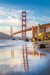 Classic vertical view of famous Golden Gate Bridge seen from scenic Baker Beach in beautiful golden evening light on a sunny day with blue sky and clouds in summer, San Francisco, California, USA
