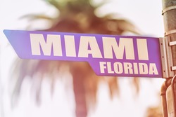Miami Florida Street Sign. A street sign marking Miami, Florida. Backed by a palm tree with a sunset flare.
