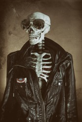 Cool Skeleton Vintage. A cool skeleton wearing a leather jacket and sunglasses, with cigarettes in his pocket and a smoke in his mouth. His heart visible in his ribcage. Edited in vintage film style.