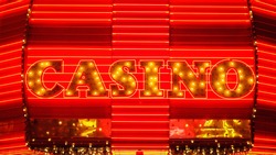 The word casino is lit up in neon lights at night on Fremont Street in Las Vegas
