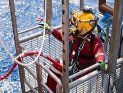 Offshore oil and gas diver in his diving cage during recovery back to deck after completing an underwater task on a newly installed jacket.