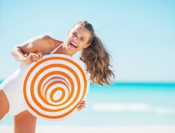 Portrait of happy young woman in swimsuit with beach hat having fun time on beach