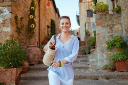Travel in Italy. happy trendy woman with straw bag having excursion in Pienza in Tuscany, Italy.