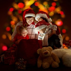 Christmas family of four persons in red hats opening lighting bag with gifts