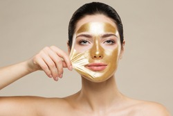 Woman peel off Gold Facial Mask. Collagen Golden Anti Aging Wrinkle Lifting Mask. Spa Beauty Treatment