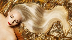 Beauty Blonde Hairstyle Model. Shiny Straight Long Golden Blond Hair Close up. Glamour Luxury Woman Perfect Skin Face Make up. Fashion Woman lying down over Gold Fabric
