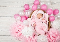 Newborn Girl sleeping in Pink Fluffy Bodysuit. Baby Birth Celebration with Balloons and Paper Flower Decoration. Cute Little Child Birthday. Dreaming Infant Portrait Top view