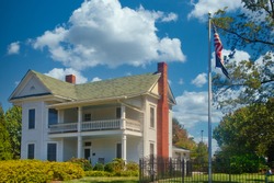A white traditional two story farmhouse with American flagpole out front