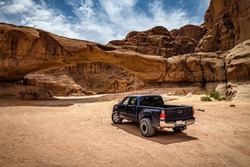 Off-road car near the rock arch in Wadi Rum desert. Jordan