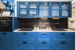 Modern red kitchen interior with black brick walls, wooden countertops with a built in sink and a cooker.  color of the year 2020 pantone classic blue