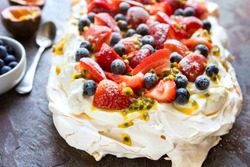 Pavlova meringue cake with berries and passionfruit.  Side view on slate.