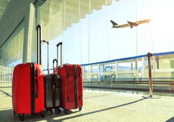 stack of traveling luggage in airport terminal and passenger plane flying over sky