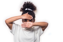 A portrait of an Afro American girl in a white casual clothes, covering her face with her hands, isolated on the white background