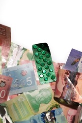 The background of Canadian dollar bills with the pills isolated on the white background