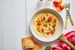 Delicious homemade egg omelette with tomatoes and parsley. Sprinkled with fresh pepper. Served with toasts. Top view with copy space.