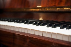 Piano keys on wooden brown musical instrument. Horizontal. View from the side