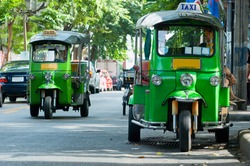 Two green tuk-tuk taxis in Bangkok. Shallow depth of field with the nearest taxi in focus.
