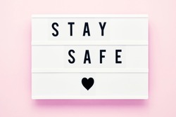 STAY SAFE written in light box on pink background. Healthcare and medical concept. Top view, copy space. Quarantine concept.
