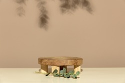 Empty round wooden podium for product presentation eucalyptus leaves on beige background abstract background.  Scene with geometrical forms. Empty showcase for eco cosmetic product presentation