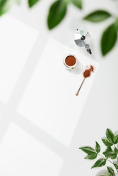 Coffee composition on light grey background, window shadow and green branches, flat lay, copy space. 