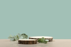 Minimal modern product display on neutral blue background. Wood slice podium and green leaves. Concept scene stage showcase for new product, promotion sale, banner, presentation, cosmetic