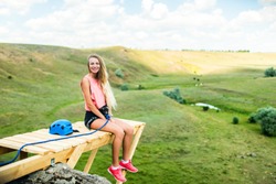 Woman sitting on a wooden ledge on a high mountain and view of the mountain landscape.