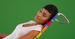 Charming young African-American woman relaxing on beach chair on green screen