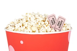 Detail of popcorn in a bucket and two tickets over a white background. Tickets on focus and shallow depth of field