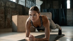 Fitness woman doing plank exercise workout in gym. Sport girl model in sportswear exercising on yoga mat, planking indoors