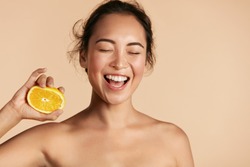 Beauty. Smiling woman with radiant face skin and orange portrait. Beautiful smiling asian girl model with natural makeup, healthy smile and glowing hydrated facial skin. Vitamin C cosmetics concept