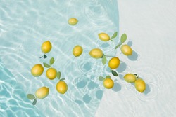 Pool Water With Lemons. Pure Aqua Surface With Glares Pattern And Floating Fresh Citrus. Clear Liquid With Sunlight Reflection In Summer.