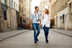 Travel. Tourist Couple Traveling, Walking On Street. Portrait Of Beautiful Young Woman And Handsome Man In Stylish Clothes Sightseeing City Attractions, Looking At Architecture. High Resolution.