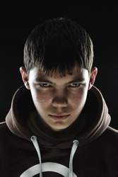 Closeup of a teenager with his hood down looking menacing