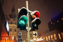 Bike traffic signs showing green and red light during a winter midnight snowfall