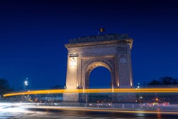 Arch of Triumph (Arcul de Triumf) building in Bucharest Romania during the evening with traffic lights at bottom of it