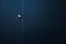 Surveillance camera on the wall of a new modern office building. Concept image for company headquarters security with space for copy.