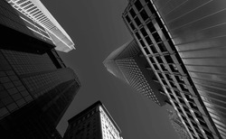 Tall skyscraper modern office buildings in Manhattan photographed from bottom to top, amazing wide angle view of this massive constructions. Travel to New York, black and white photo.