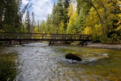 Simple, rustic wood bridge over Kintla Creek in Glacier National Park at Kintla Lake area creates tranquil forest and water scenic in Montana