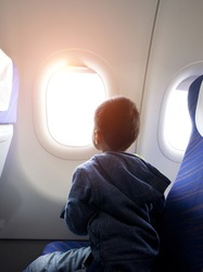 asian boy looking outside of airplane window
