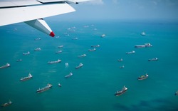 Rows of industrial cargo ships queuing on the ocean outside Singapore. International maritime freight stretching out to the horizon. Aerial view of globalisation of transportation.