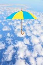 Wind of change concept.Umbrella in Ukrainian flag colors flies in sky over white clouds.Mary Poppins Umbrella.