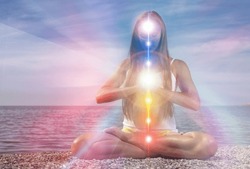 Yoga meditation outdoors. Glowing seven all chakra. Woman sits in a Upward Salute pose on beach sunset view, Kundalini energy. girl practicing.