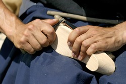 a man making shoes with his hands and using a knife